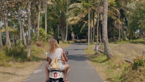 pareja de turistas en motocicleta en una isla tropical mujer feliz celebrando la libertad con los brazos levantados disfrutando de un viaje por carretera de vacaciones con su novio en motocicleta vista trasera