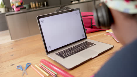 African-american-girl-in-online-class-using-headphones-and-laptop-with-copy-space,-slow-motion