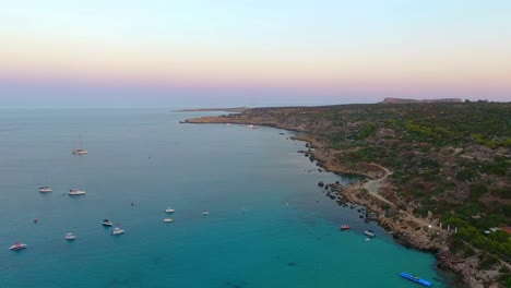 Vistas-De-Drones-De-La-Mundialmente-Famosa-Playa-De-Konnos-En-La-Isla-Mediterránea-De-Chipre-A-última-Hora-De-La-Tarde-Después-Del-Atardecer-Con-Agua-De-Mar-Turquesa-Clara