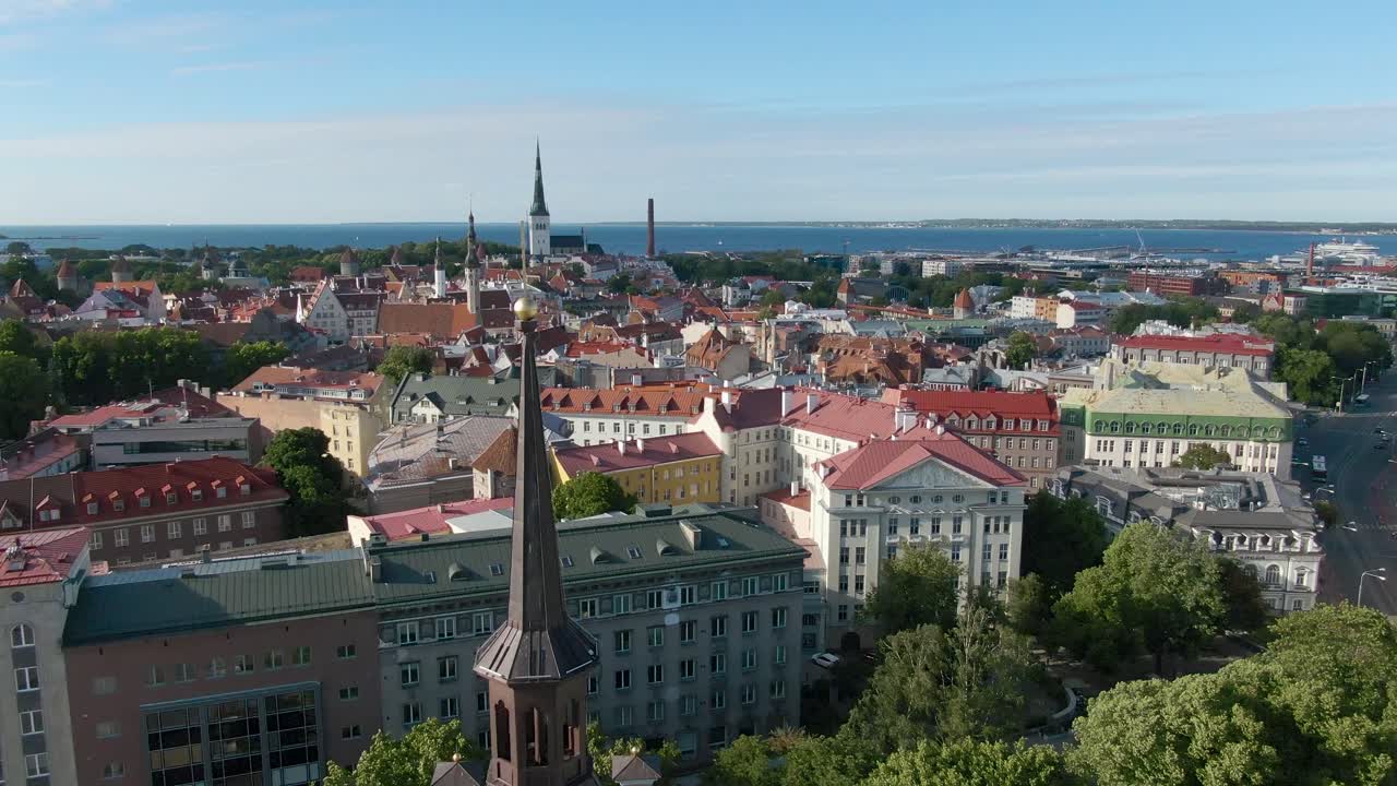 Una ripresa drone in movimento di una croce dorata in cima a un campanile, con la città vecchia di Tallinn e i suoi edifici medievali sullo sfondo, in 4K.