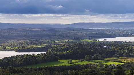 Lapso-De-Tiempo-Del-Paisaje-Rural-Con-El-Castillo-De-Kilronan-En-La-Distancia-Rodeado-De-Lago,-Bosque-Y-Colinas-Durante-Un-Día-Nublado-Visto-Desde-Arriba-Del-Lago-Meelagh-En-El-Condado-De-Roscommon-En-Irlanda