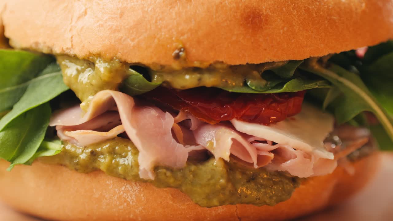 Mortadella ham sandwich, Traditional italian focaccia filled with thin pesto slices of mortadella, served by chef man in cafe restaurant. Macro of traditional italian spanish tapas antipasti.