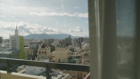 Wide-shot-from-balcony-over-cityscape-of-Malaga-during-sunlight-and-mountains-in-background