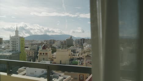 wide shot from balcony over cityscape of malaga during sunlight and mountains in background