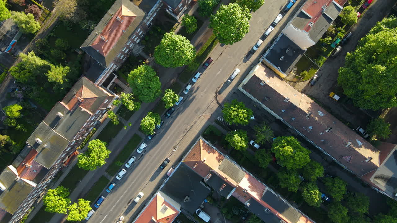 Aerial Drone Roll Around Vehicles Parked On Roadside Along with Buildings On A Sunny Day In Gdansk, Poland - top down view