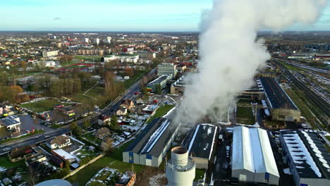 industrial power plant with steam billowing out of chimney over a city in europe