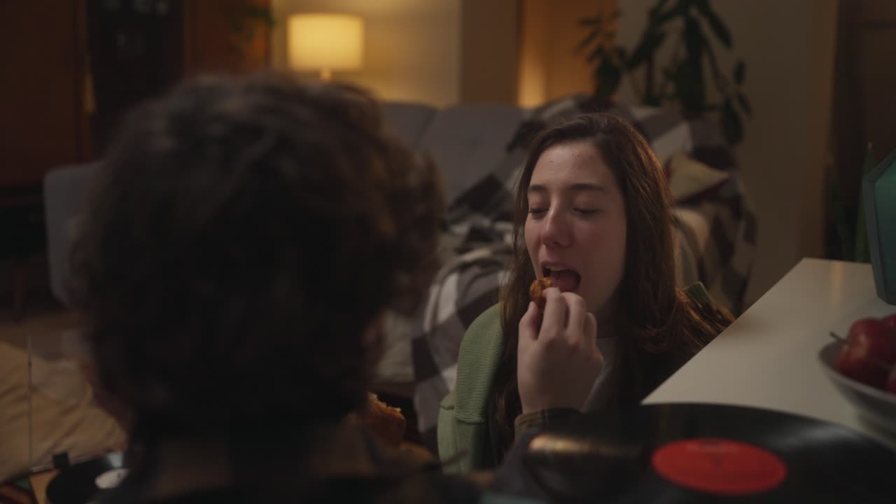 Two people eating at home with a vinyl record nearby