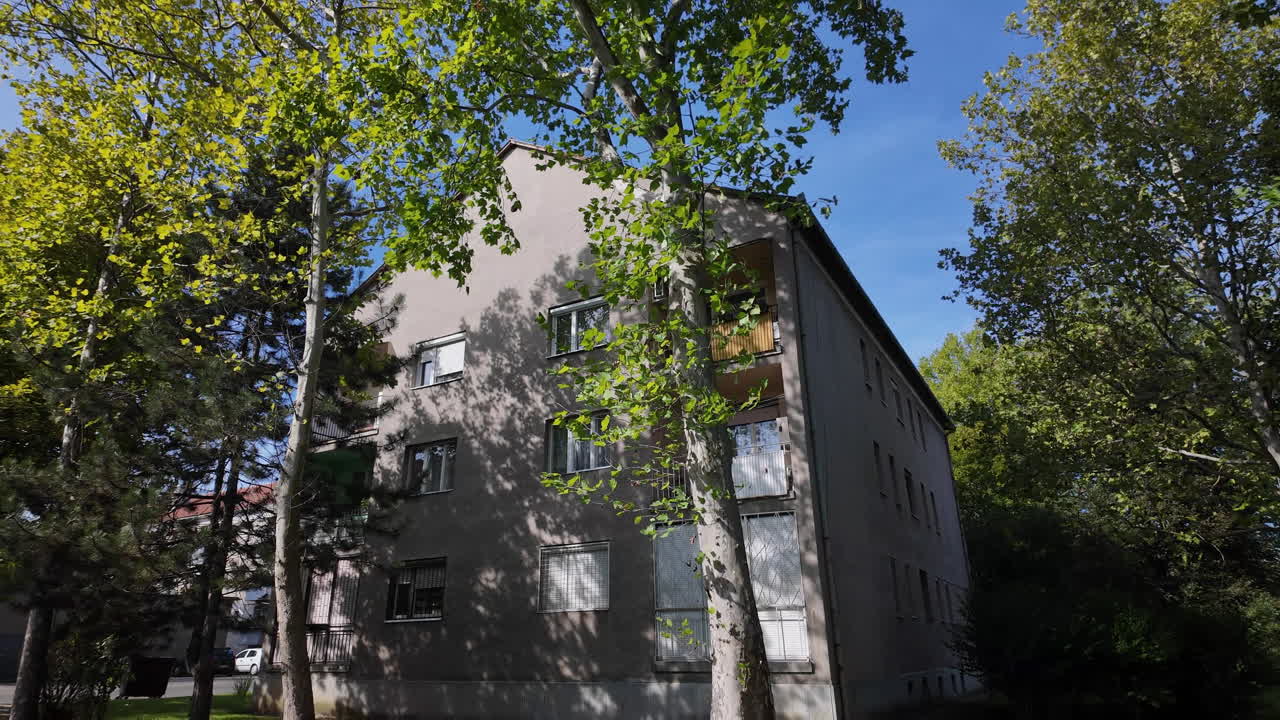 Apartment building among green trees under blue sky
