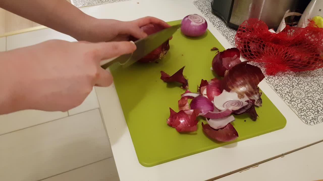 Caucasian woman cooking and cutting up purple onion