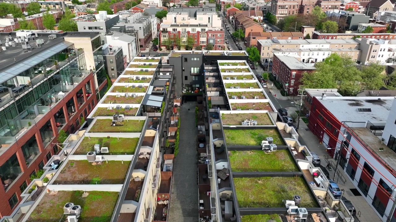 Apartments in American city with green sedum roofs with grass and turf growing to protect our planet. Climate change initiatives in urban housing areas. Aerial establishing shot.