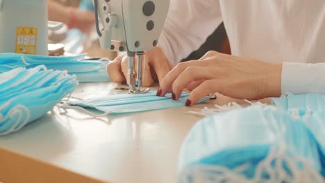 woman hands using the sewing machine to sew the face medical mask during the coronavirus pandemia. home made diy protective mask against virus.