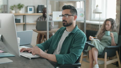 hombre de oriente medio con discapacidad trabajando en la computadora en la oficina