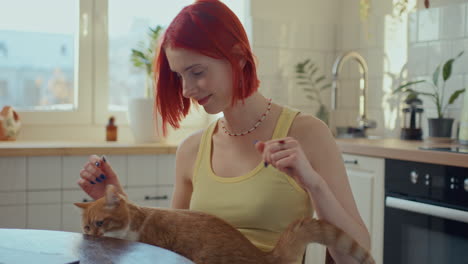 red-haired girl petting cat and smiling in kitchen filled with sunshine