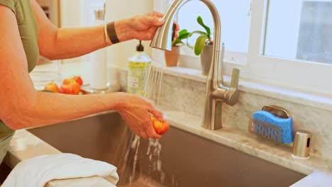 Una-Mujer-Adulta-Lavando-Manzanas-En-Un-Fregadero