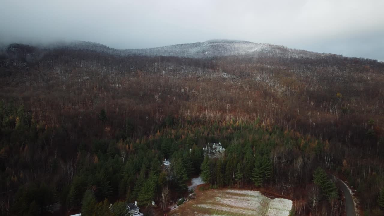fotografía aérea del bosque y la montaña con un poco de nieve y nubes en la parte superior