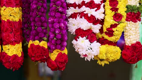 vibrant flower garlands hang in a market stall, camera panning smoothly to reveal intricate floral arrangements under bright, natural lighting in singapore
