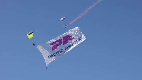 skydivers with large banner in clear blue sky