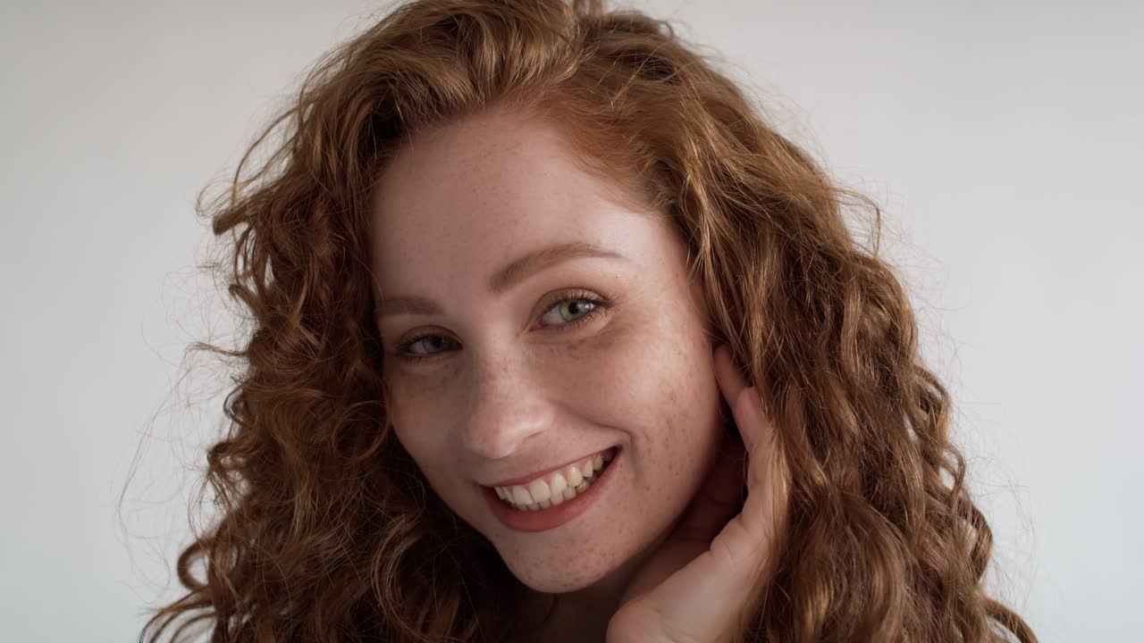 retrato en primer plano de una joven caucásica riendo sobre un fondo blanco.