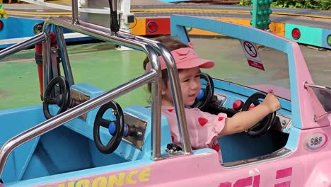 Una-Niñita-Divertida-Finge-Conducir-Un-Automóvil-Montando-Una-Colorida-Montaña-Rusa-Para-Niños-En-El-Parque-De-Diversiones-De-Seúl-Land-En-Vacaciones-De-Verano-En-Corea-Del-Sur---Acción-De-Seguimiento