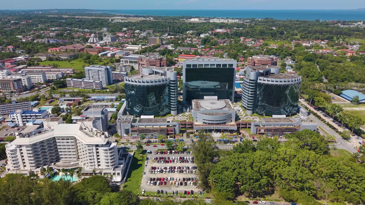 Drone footage flying over Labuan Financial Park in Victoria, Malaysia. The shot showcases the modern high-rise office towers, surrounding development, and roads