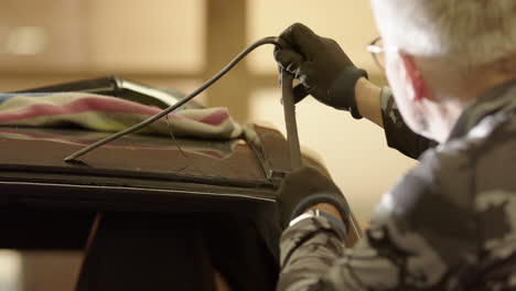 workshop technician removes old adhesive from windscreen aperture