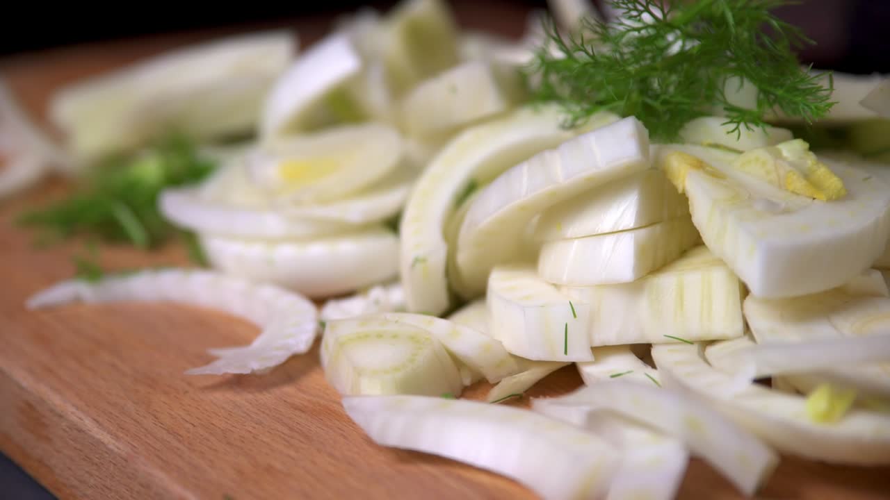 el chef agarra un puñado de hinojo picado de la tabla de madera en la cocina