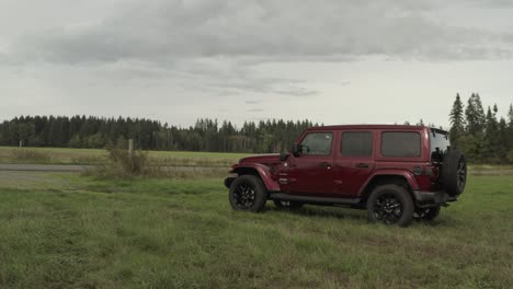 Toma-Panorámica-De-Drones-De-Un-Jeep-Wrangler-Rojo-En-Una-Granja-En-4k