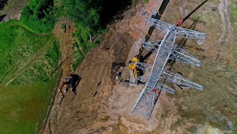Crew-of-workmen-working-on-a-electrical-transmission-tower-with-a-crane---aerial-overlook