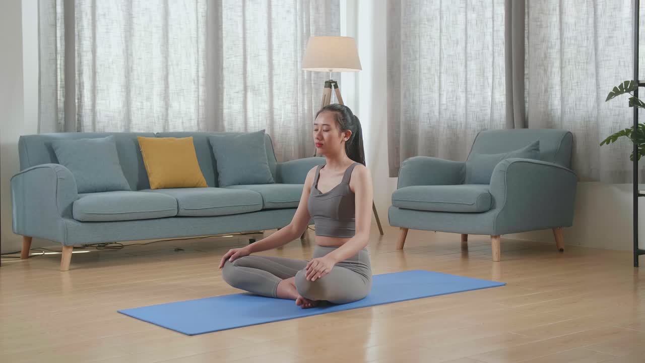 젊은 아시아 운동선수 여성이 집에서 요가 매트에서 운동하는 동안 명상합니다. 건강한 생활 방식, 피트니스, 웰빙 및 마인드풀니스