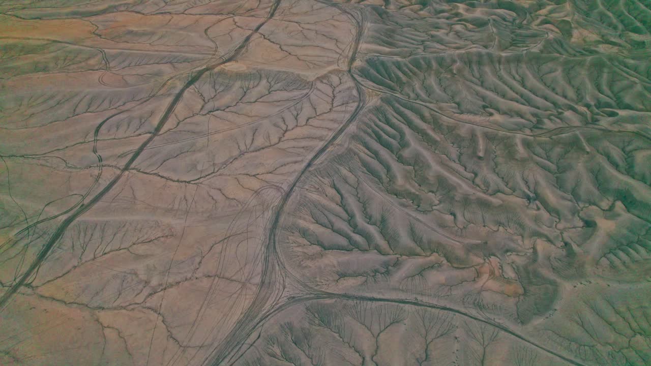 4k Drone of Factory Butte badlands, featuring carved ravines, jagged ridgelines, and striking desert contours etched with rich textures and muted earth tones, an awe-inspiring, alien-like landscape.