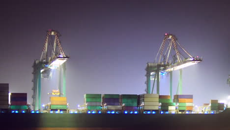 Loading-a-container-ship-at-night,-ZOOM-OUT