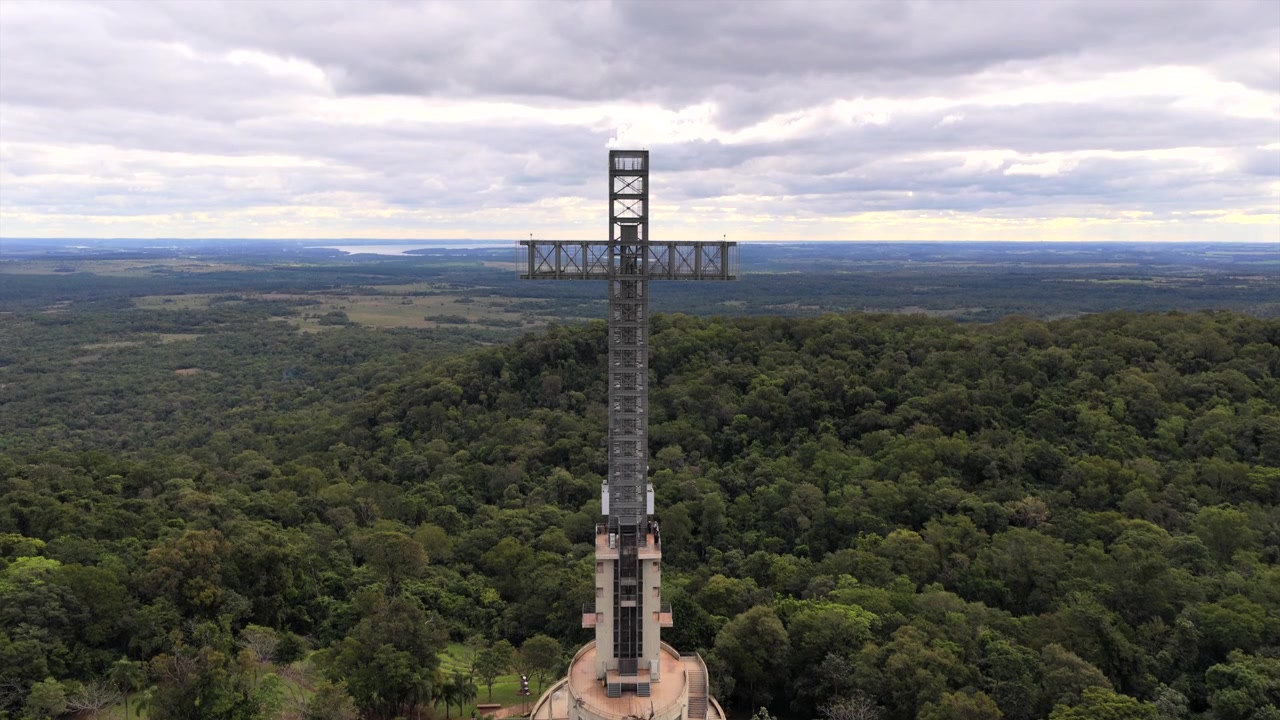 Parque Temático de la Cruz a Santa Ana, Misiones, Argentina, con una monumentale torre a croce in acciaio sopra il paesaggio della Foresta Atlantica dell'Alto Paraná e la volta della foresta pluviale subtropicale, drone statico.