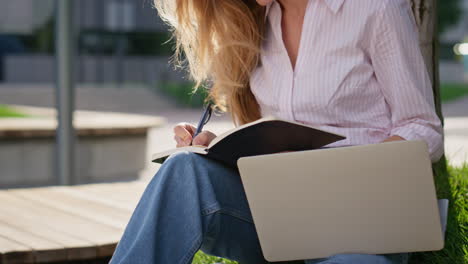 beautiful woman writing notes in park closeup. focused freelancer work outside