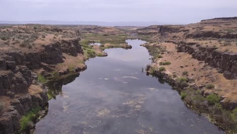 aerial: stagnant pond by small highway in channeled scablands of wa