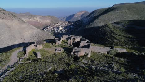 Aerial-orbit-shot-of-the-ruins-of-the-old-customs-building-in-the-Apache-Hill-with-the-Real-de-Catorce-town-in-back,-San-Luis-Potosi,-Mexico