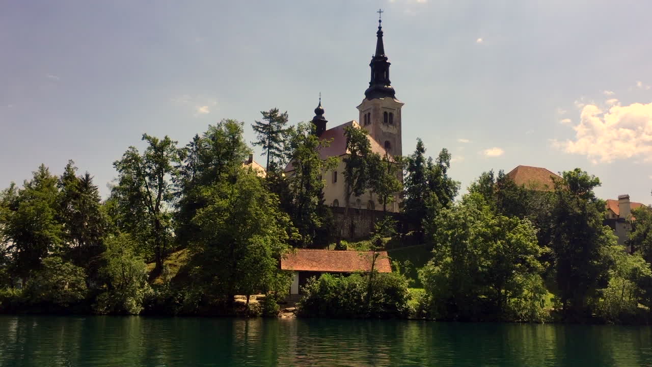 Lago di Bled Chiesa dell'Assunzione di Maria con campanile in Slovenia, HD, panoramica dalla barca Pletna alla chiesa