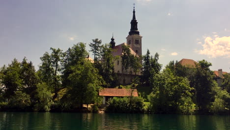 Bleder-See-Kirche-Mariä-Himmelfahrt-Mit-Glockenturm-In-Slowenien,-HD,-Schwenk-Vom-Pletna-Boot-Zur-Kirche