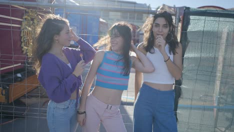 three girls enjoying lollipops at a carnival