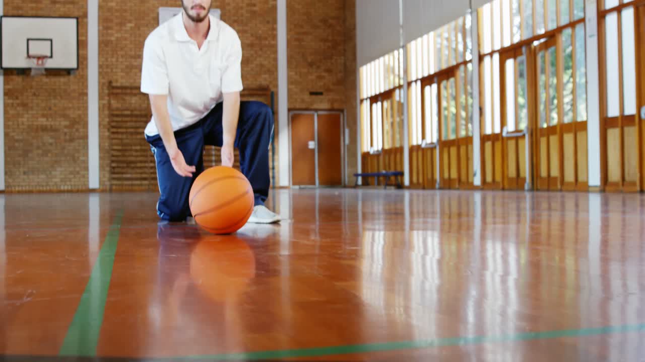 maestro de deportes sosteniendo una pelota de baloncesto en la cancha de baloncestro