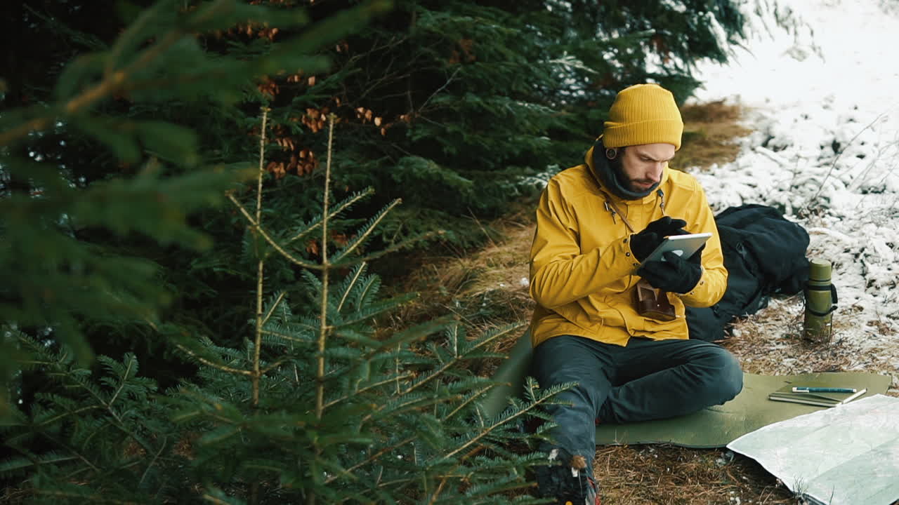 Man using a tablet in a snowy forest