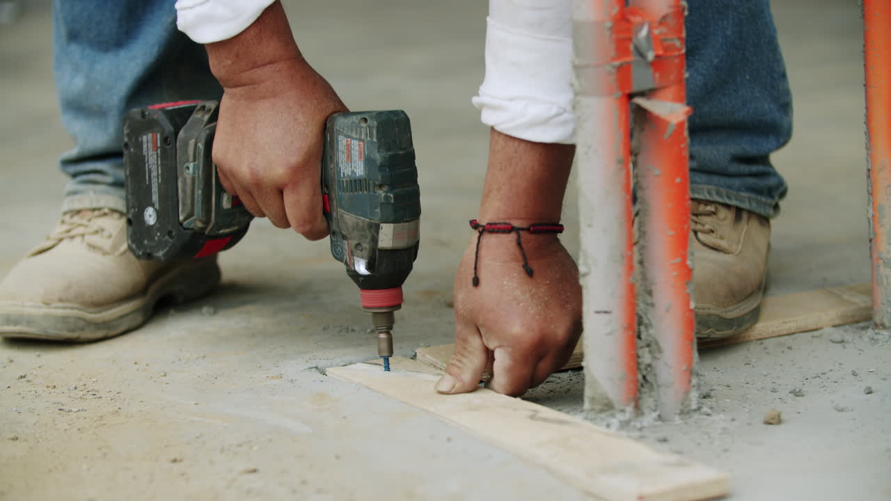 Primer plano de un trabajador usando un taladro eléctrico en una obra de construcción