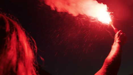 woman waving flare on beach at night