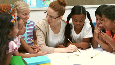 Teacher-and-pupils-working-at-desk-together