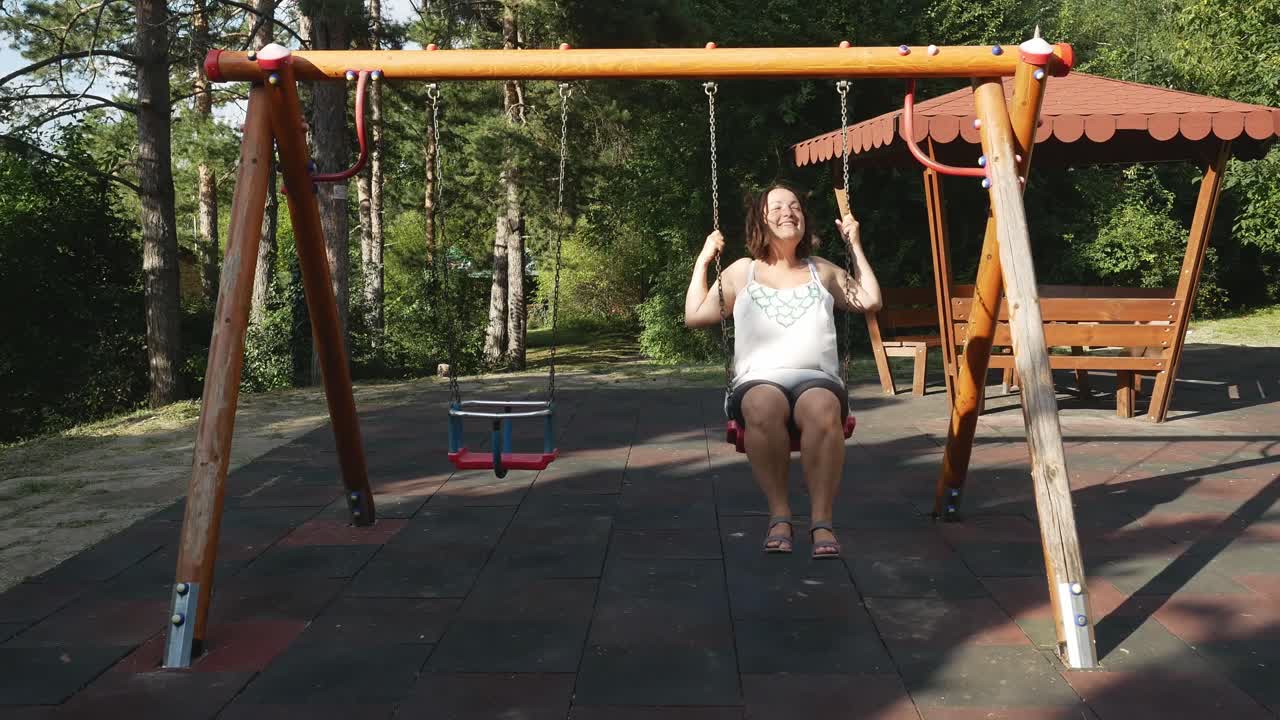 mujer divirtiéndose en el patio de recreo de los niños en el parque