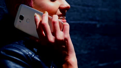 mujer de cabello rosa hablando por teléfono móvil en el callejón 4k