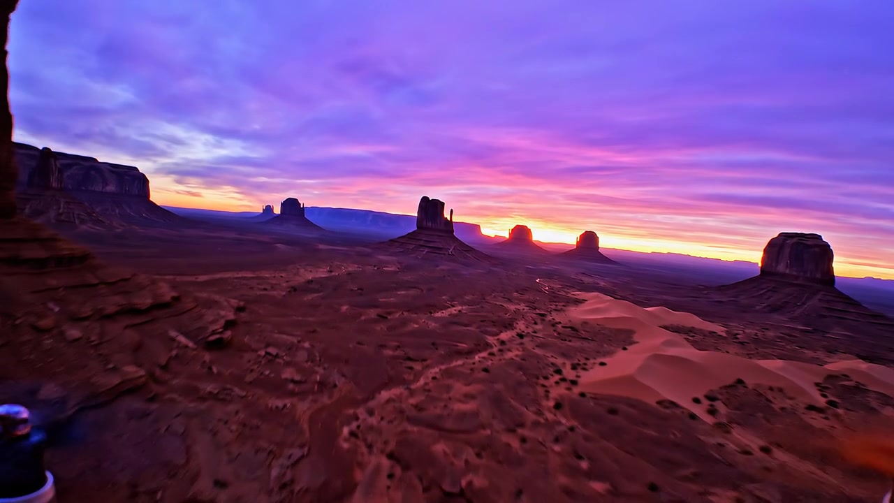 Dramatic sunrise over desert rock buttes and sand dunes