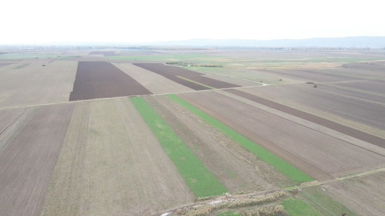 Drone Camera Pan over Brown and Green Agricultural Farmland, daytime, Aerial