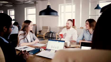 young female employee speaks at team meeting. happy mixed ethnicity creative department workers discuss project 4k