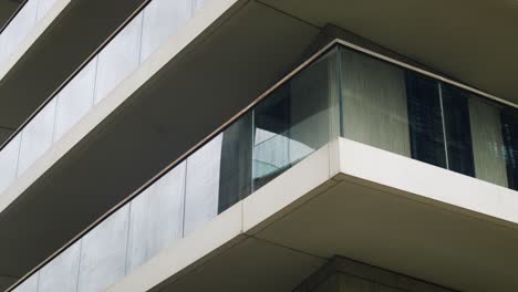 detail shot of a sleek apartment building featuring glass railings, clean architectural lines, and reflective surfaces, showcasing modern urban living