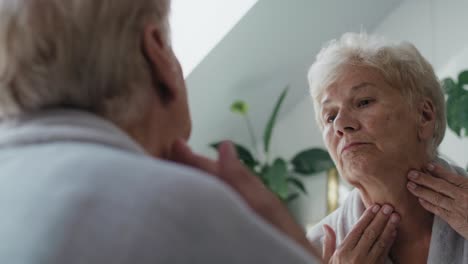 Mirror-reflection-on-senior-woman-checking-skin-condition-in-the-morning